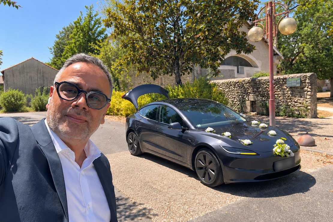 Le chauffeur en costume à côté de sa Tesla graphite ornée de fleurs blanches.