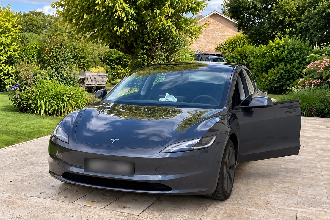 Tesla Model 3 graphite vue de trois quarts avant dans un jardin arboré.