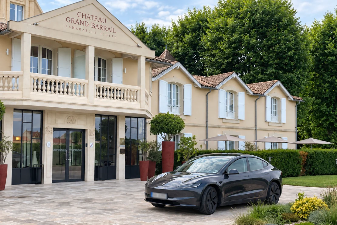 Tesla graphite devant l’entrée du Château Grand Barrail et sa façade claire.